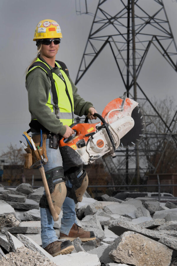 Woman cement mason holding giant Stihl saw